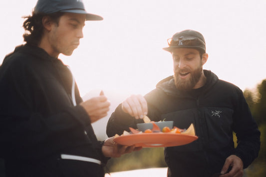 Two friends sharing snacks outdoors in warm evening light