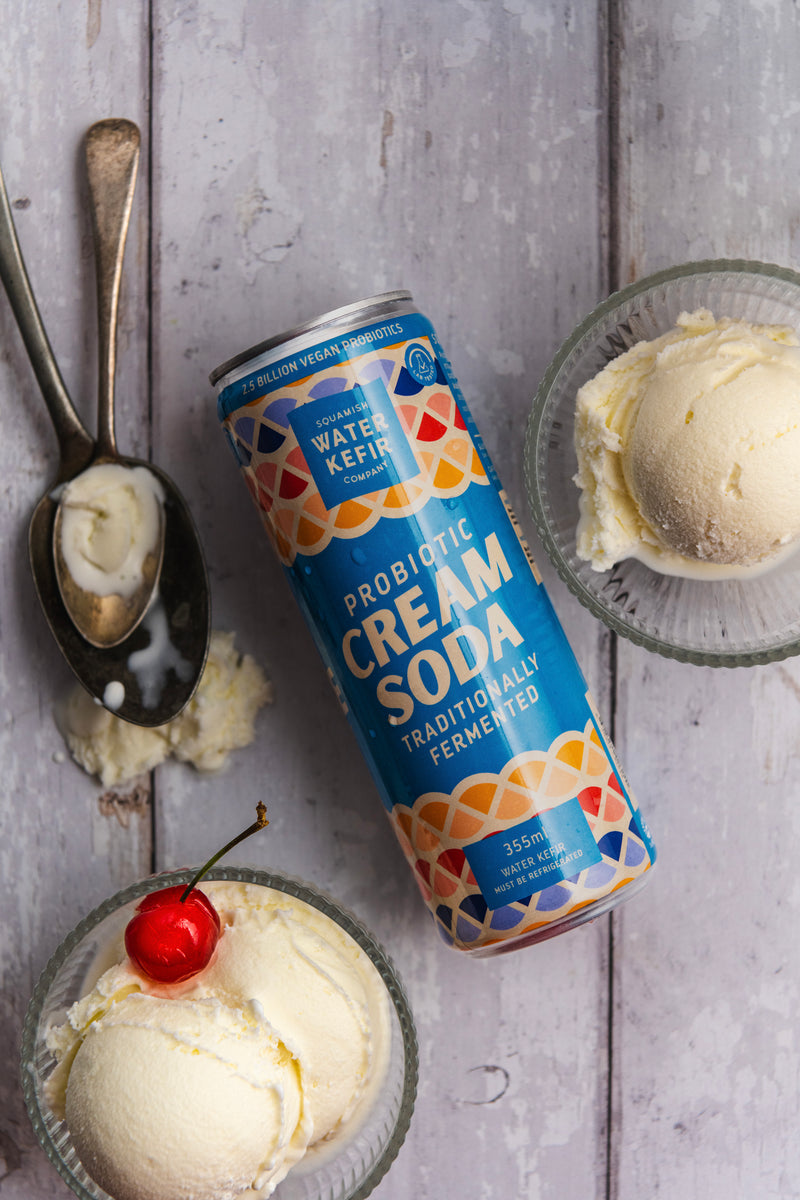 Squamish probiotic cream soda can displayed with two bowls of ice cream and a cherry on rustic wooden surface