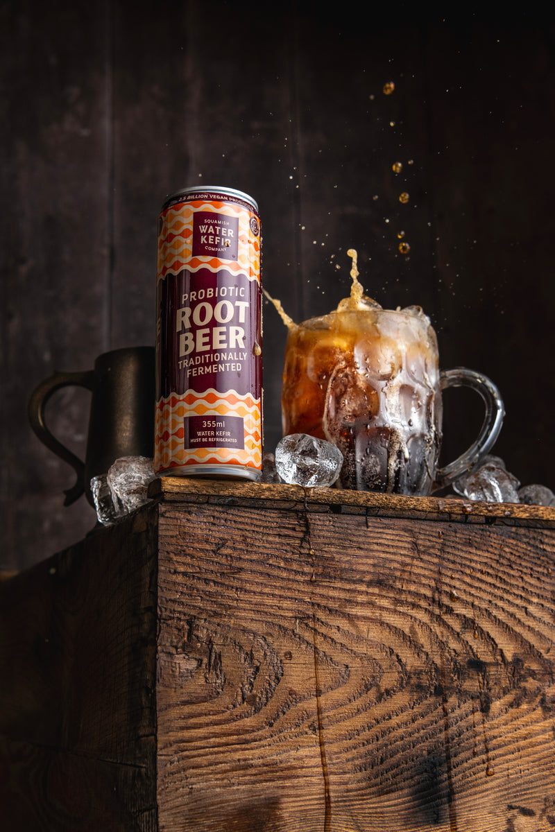 Root beer can and mug with ice on a wooden surface against a dark background