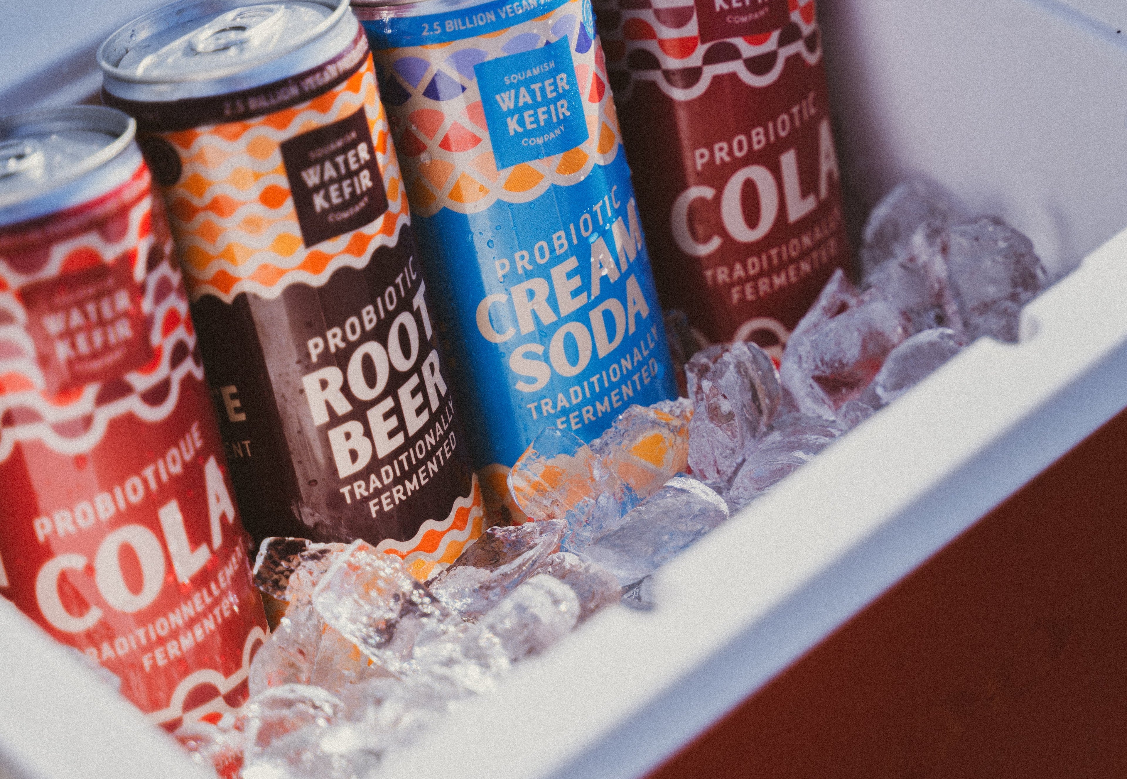 Assorted Squamish Water Kefir probiotic drinks in various flavors displayed in a cooler filled with ice