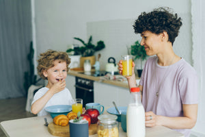 Woman and child enjoying time together at a kitchen table with healthy food and drinks during family meal
