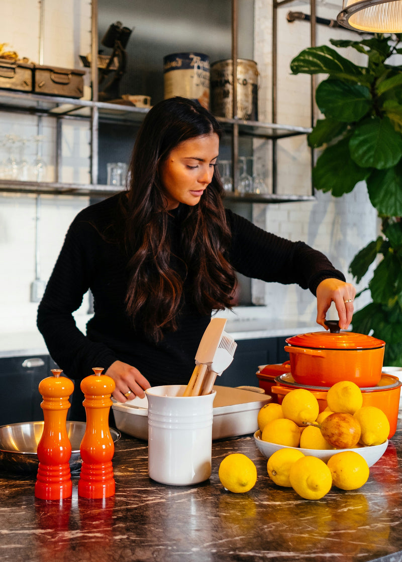 Woman preparing food in a modern kitchen with various ingredients and utensils.